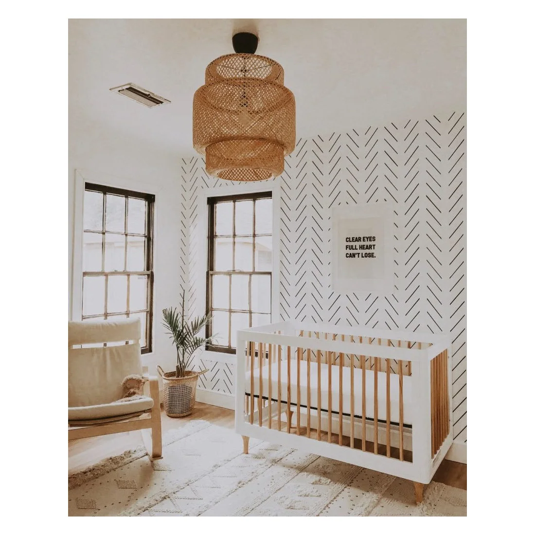 White and wood crib beside a fine black line-pattern wall, pale chair and woven pendant shade