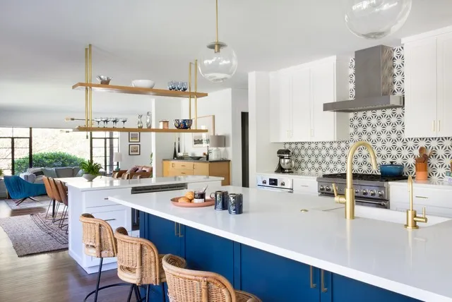 A bright blue island carries a pale counter and warm brass faucet beside woven seating.