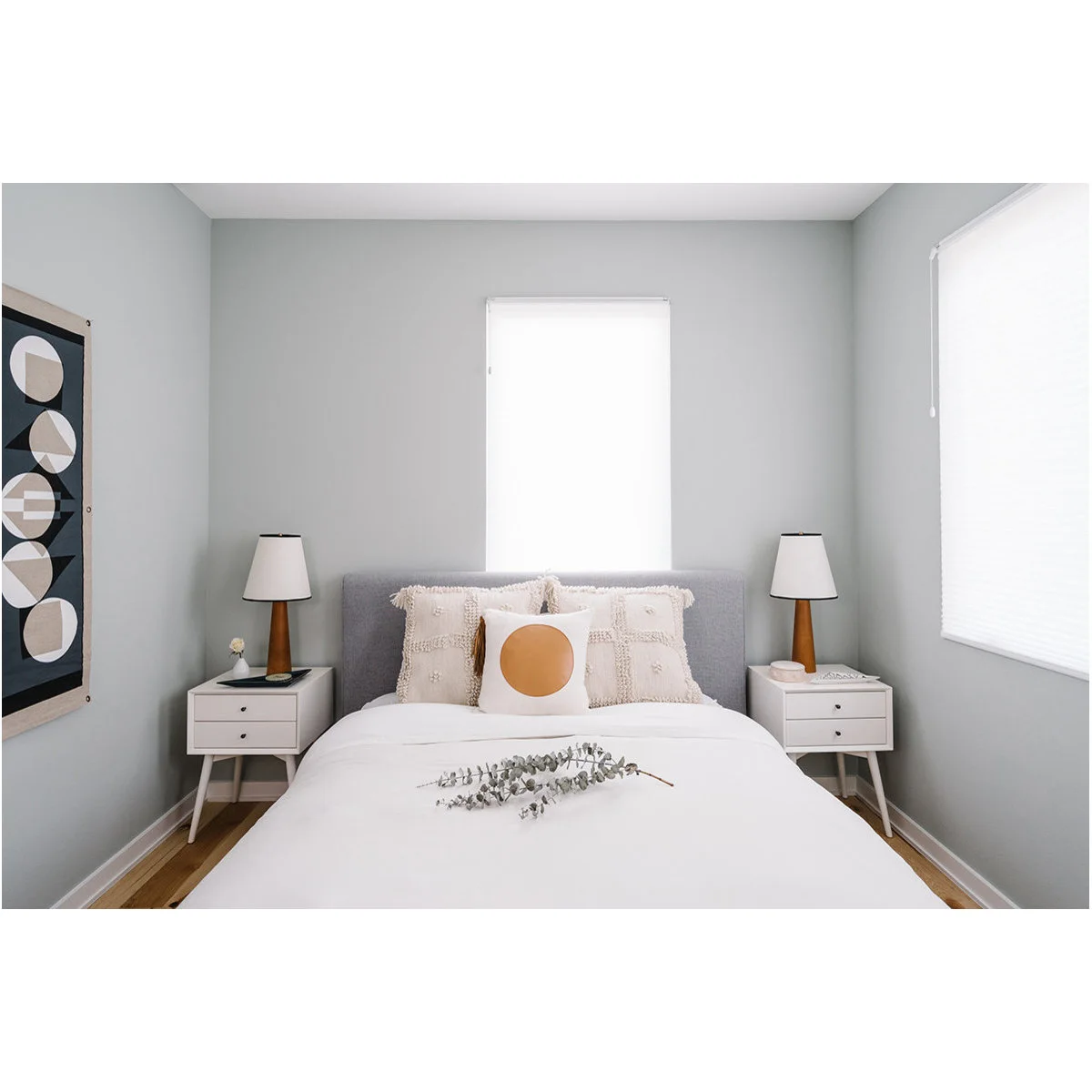 White two-drawer bedside tables with tapered legs and matching lamps in a gray bedroom