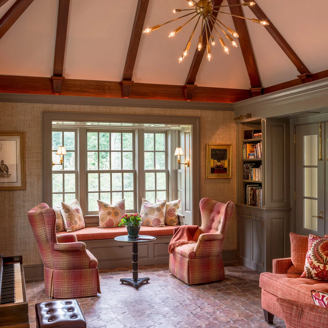 Brown shaped terracotta tiles cover a reading room with red checked chairs and a window seat.