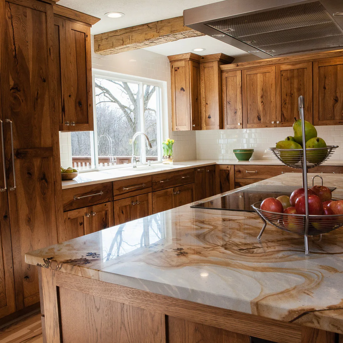 Rustic wood cabinets beside a white tile backsplash and a strongly veined island counter