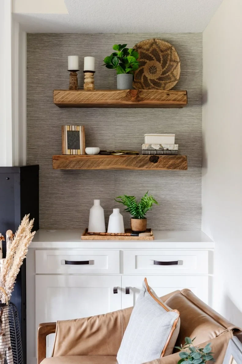 Two thick timber shelves sit above a white alcove cabinet with drawers and doors against a textured gray backing.