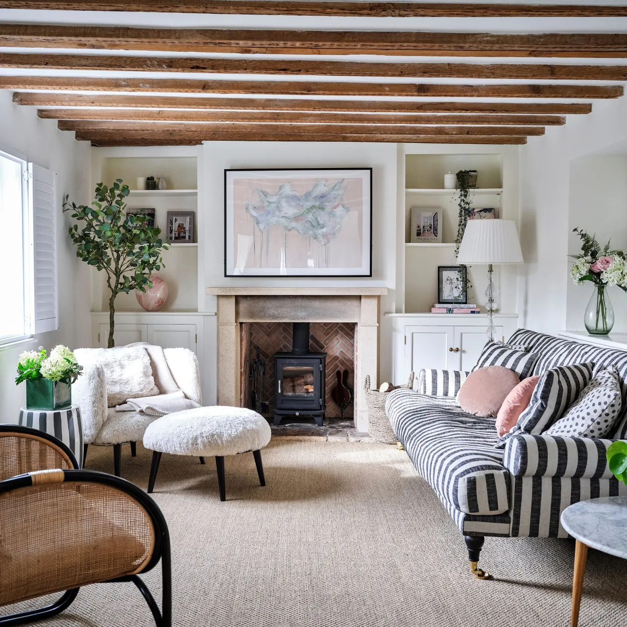 A striped sofa shares a small room with a pale chair and a stone fireplace