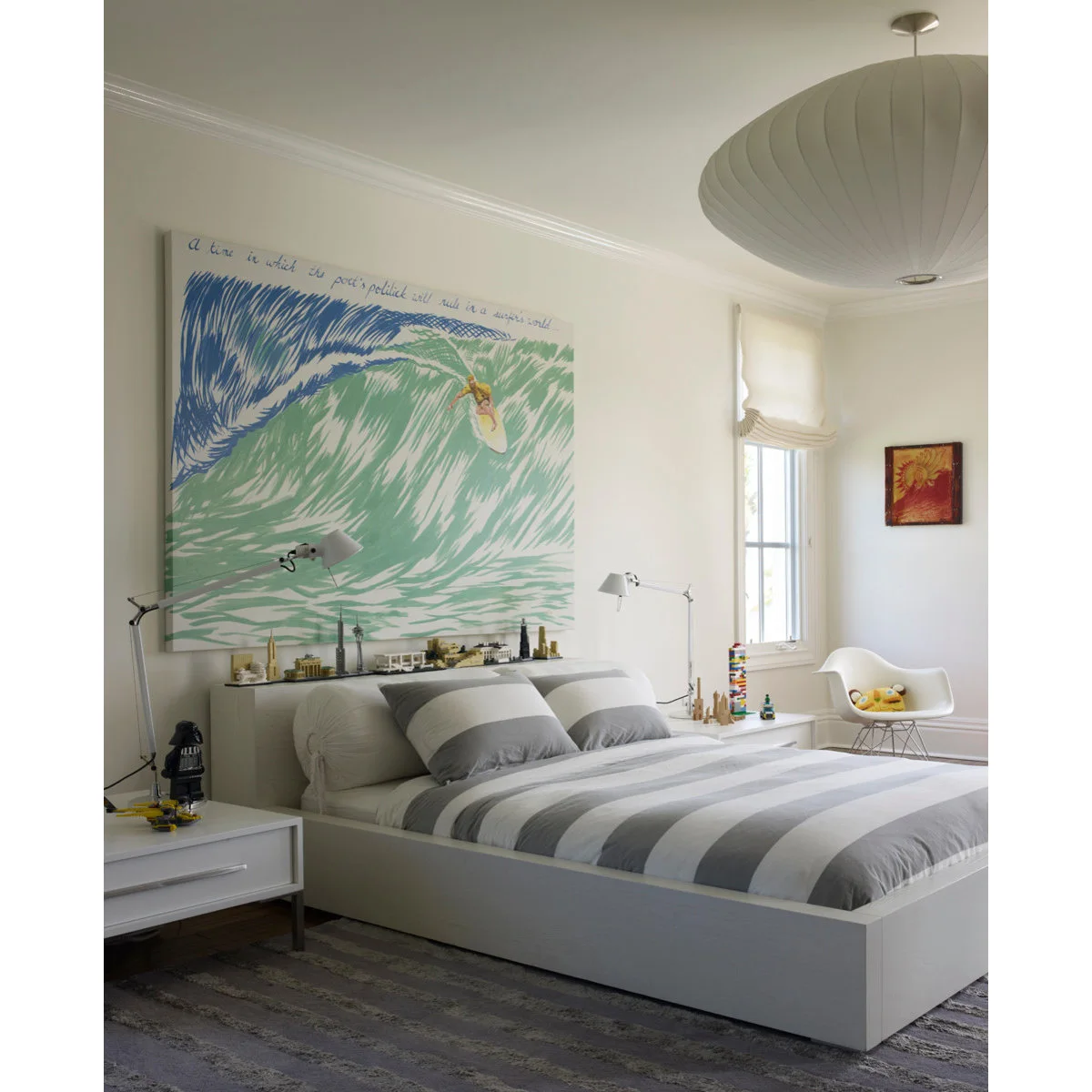Boy’s room with a large illustrated wave above a gray and white striped bed