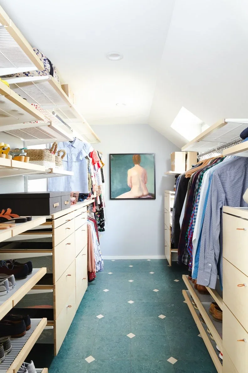 An attic closet uses open pale timber and wire shelving on both sides of a clear central aisle.
