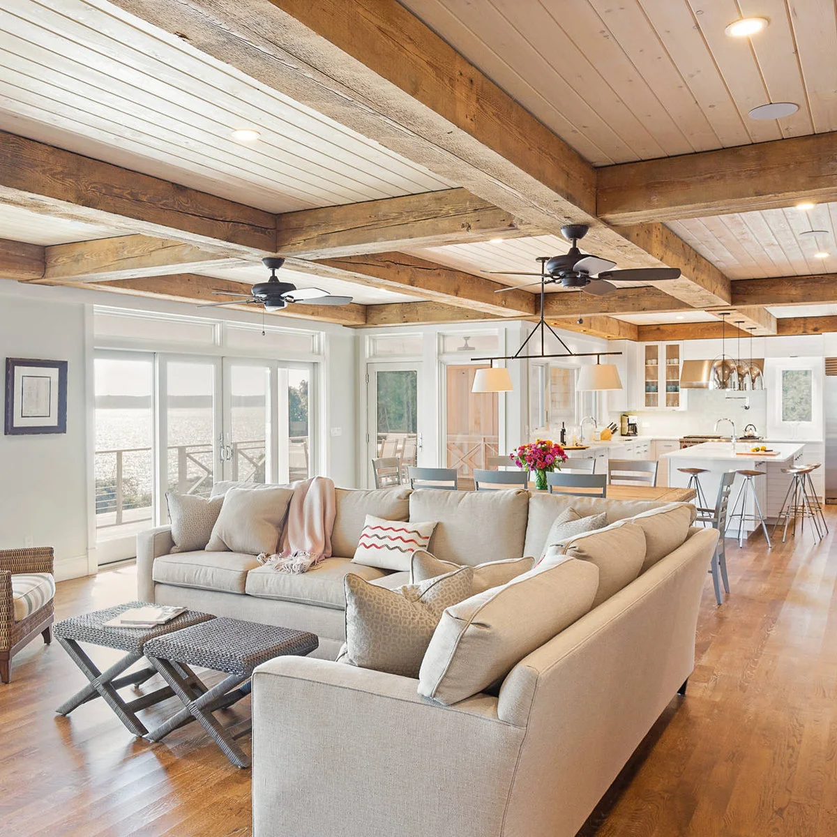 Open living area with a cream sectional, two small woven-top tables and a dining table behind