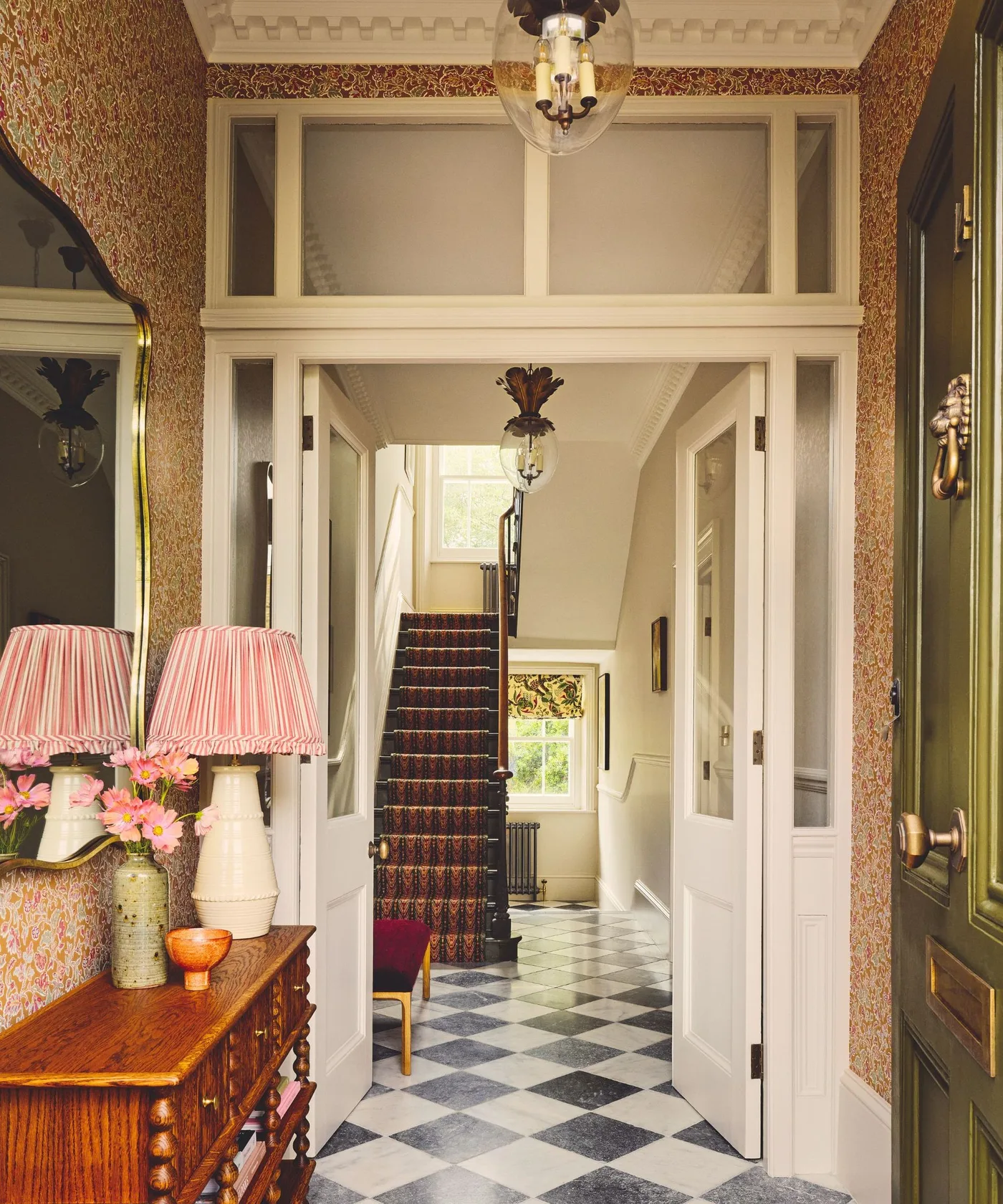 Country entrance with small rust-colored floral wallpaper, wood console and pale doorway trim