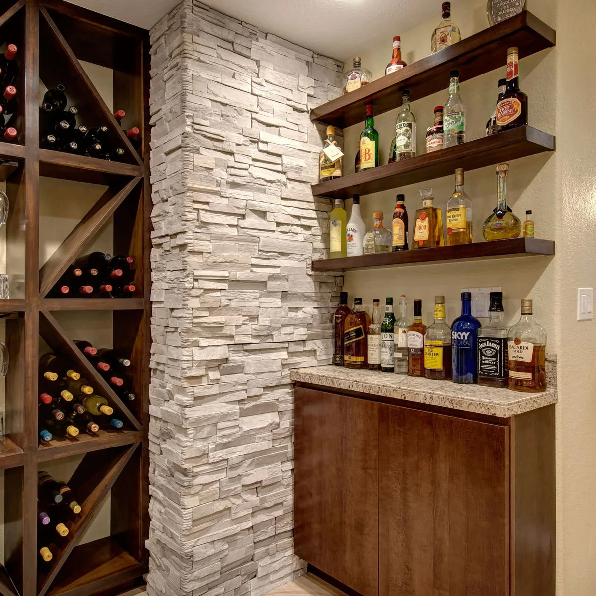 Basement bar corner with wood-colored shelves, bottle racks and pale textured column
