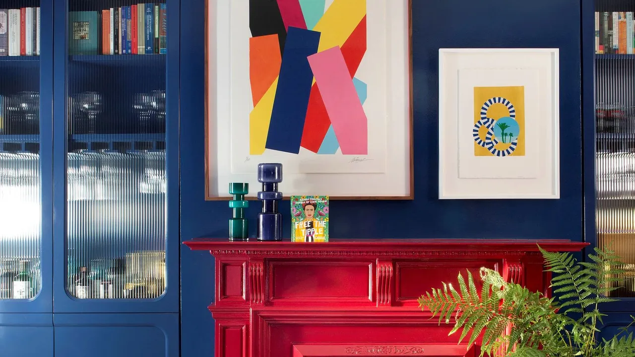 Blue glazed storage stands beside a bright red mantel beneath graphic artwork.