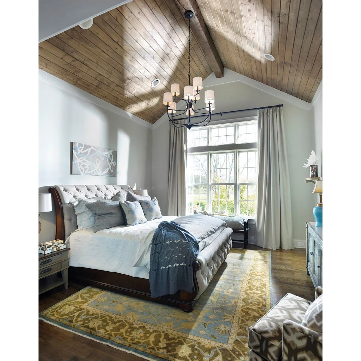 Grey upholstered bed and pale grey walls beneath a wood-planked vaulted bedroom ceiling