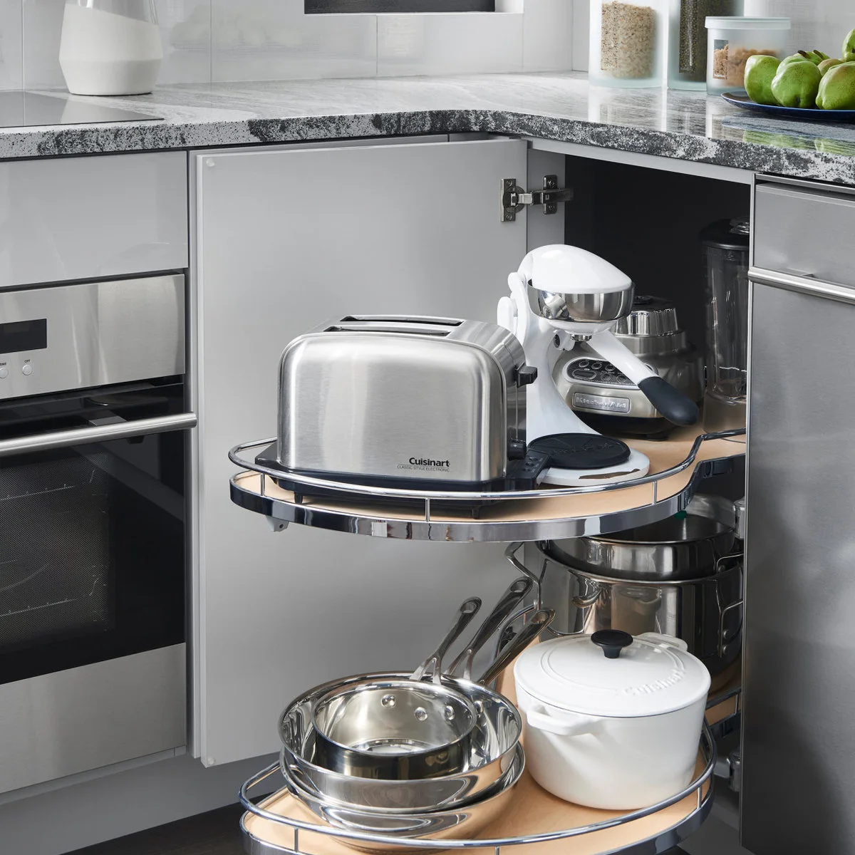 Gray corner cupboard with toaster and mixer on an upper swing-out shelf and pans below