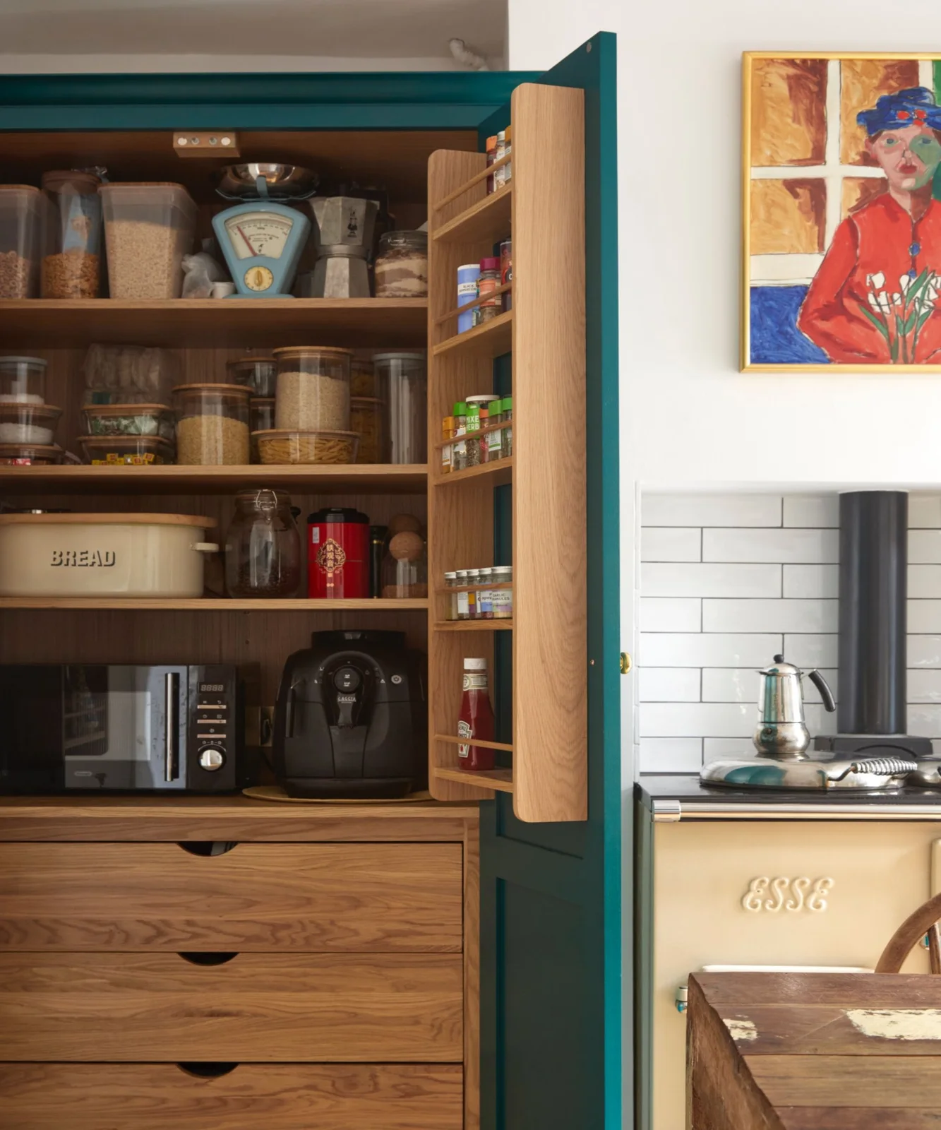 Green larder with wooden door racks, clear food containers and drawers below
