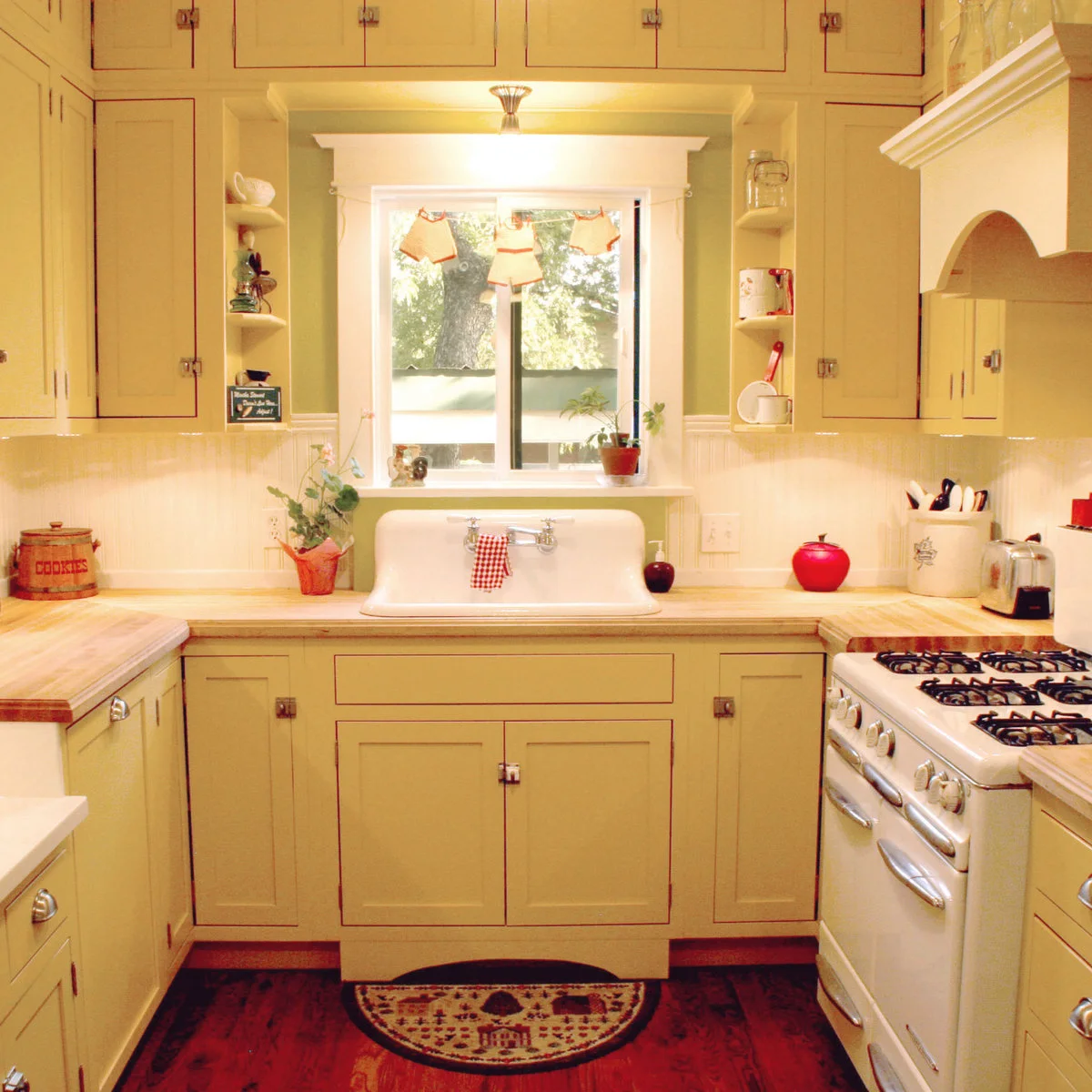 Traditional yellow kitchen cabinets with red edging, a pale sink and white beadboard