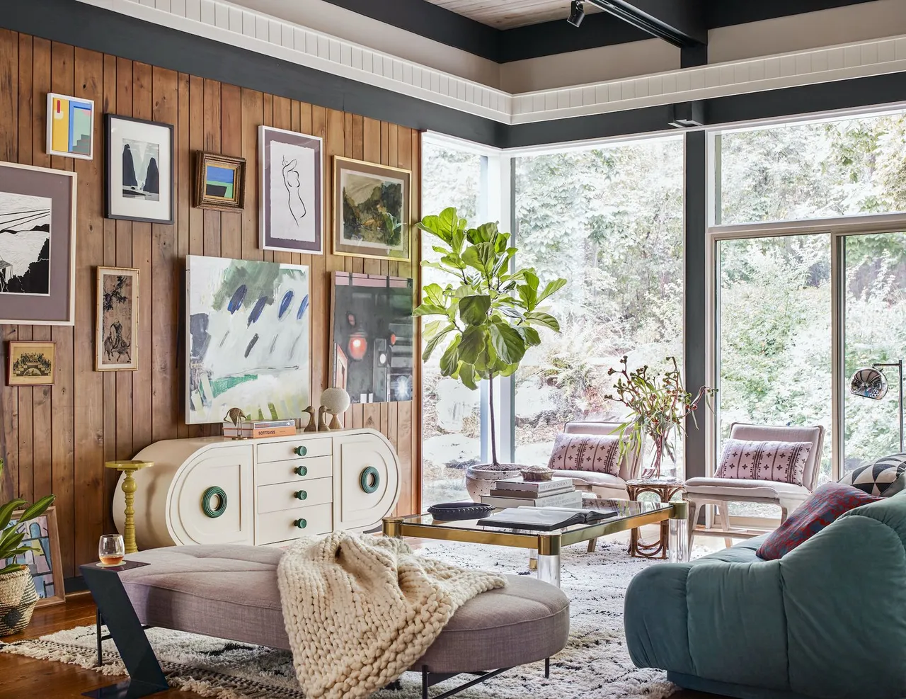 Framed gallery on a timber wall above a pale upholstered chaise and patterned rug beside mixed seating
