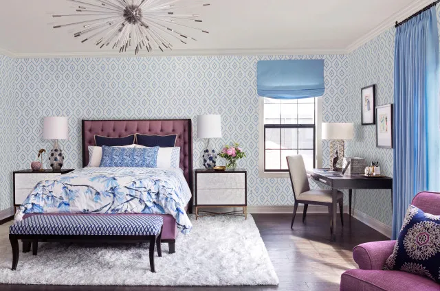 Fine pale wall pattern surrounds a tufted darker headboard and blue curtains.