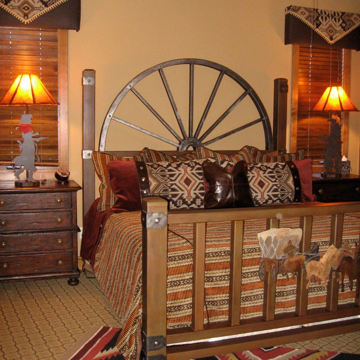 Western bedroom with a wagon-wheel headboard, geometric patterned bedding, warm lamps and wood window blinds