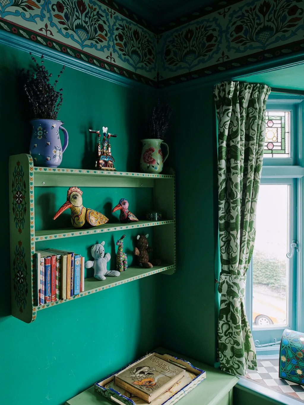 Deep green nursery walls surround a painted display shelf, patterned curtains and a decorative botanical border near the ceiling