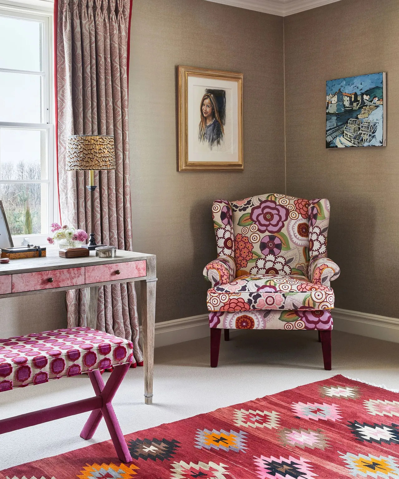 A patterned upholstered chair sits beside a painted desk and small stool.