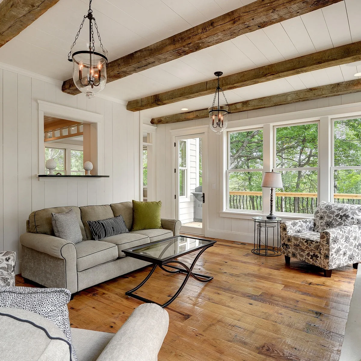 White flat ceiling boards between rough dark beams above a gray sofa