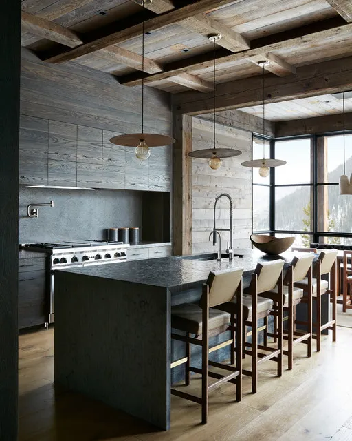 A solid black island anchors a kitchen beneath pale exposed timber beams.