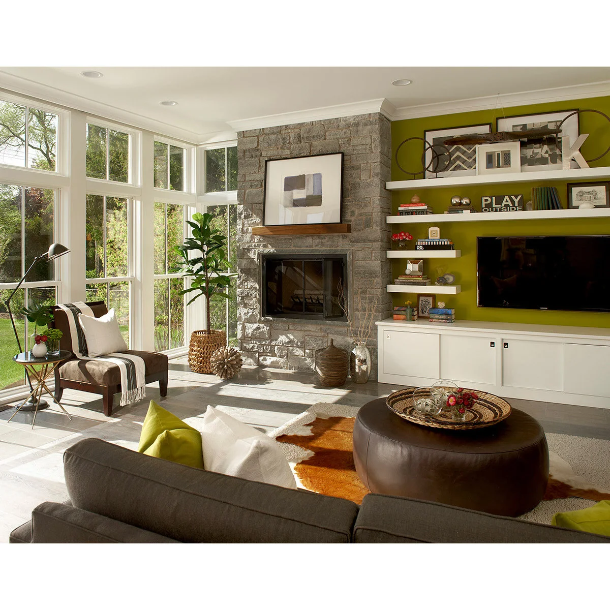 Two white picture ledges with layered frames, books and small objects above a television on a bright green wall.
