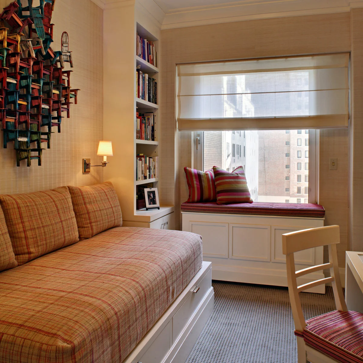 Compact apartment room with striped window-seat cushion, white cupboards below and shelves beside a daybed