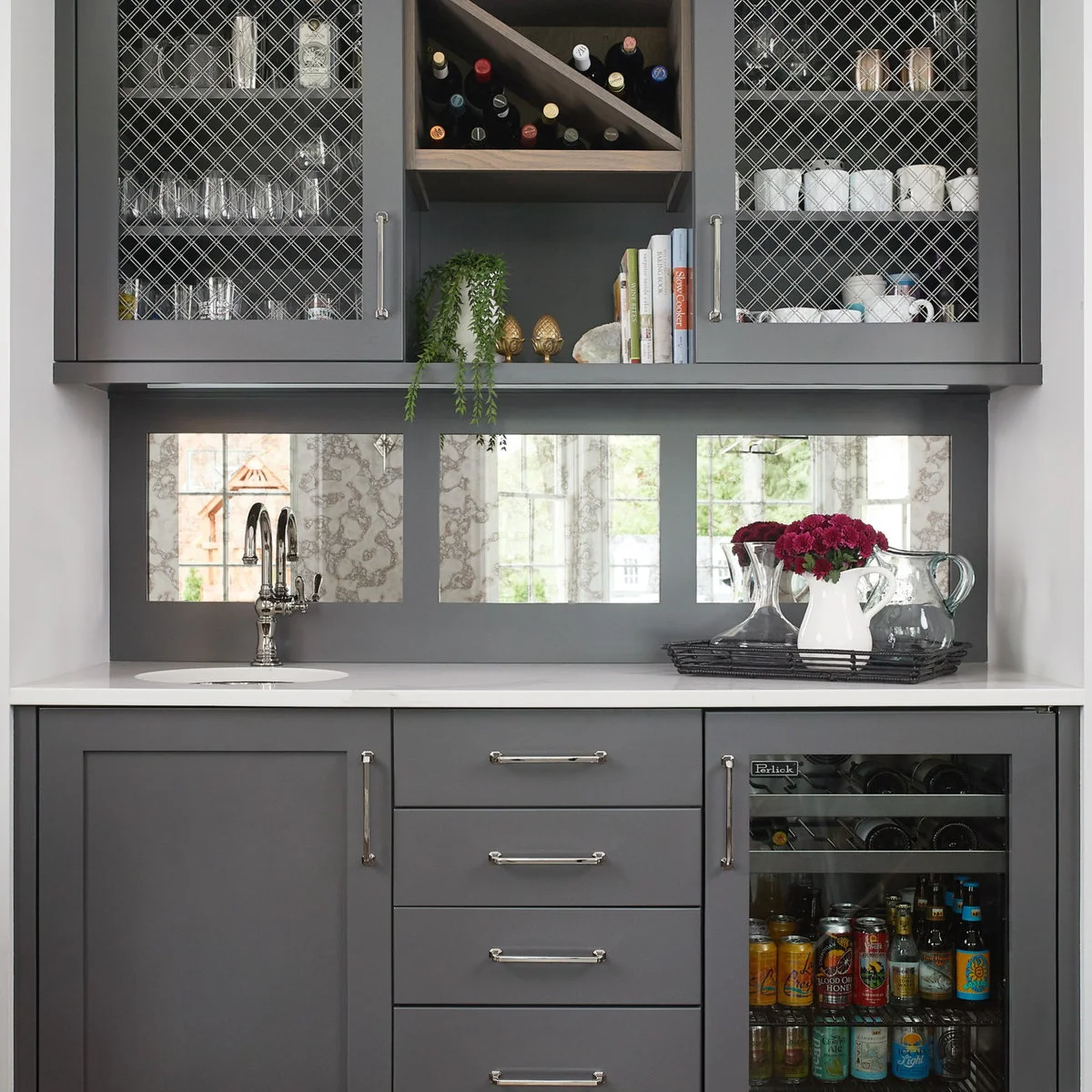 Gray mini bar with mesh-front display cupboards, diagonal bottle storage, mirrored panels and lower drawers