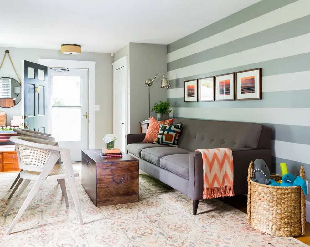 Broad green-gray and pale stripes run behind a small gray sofa and four framed pictures