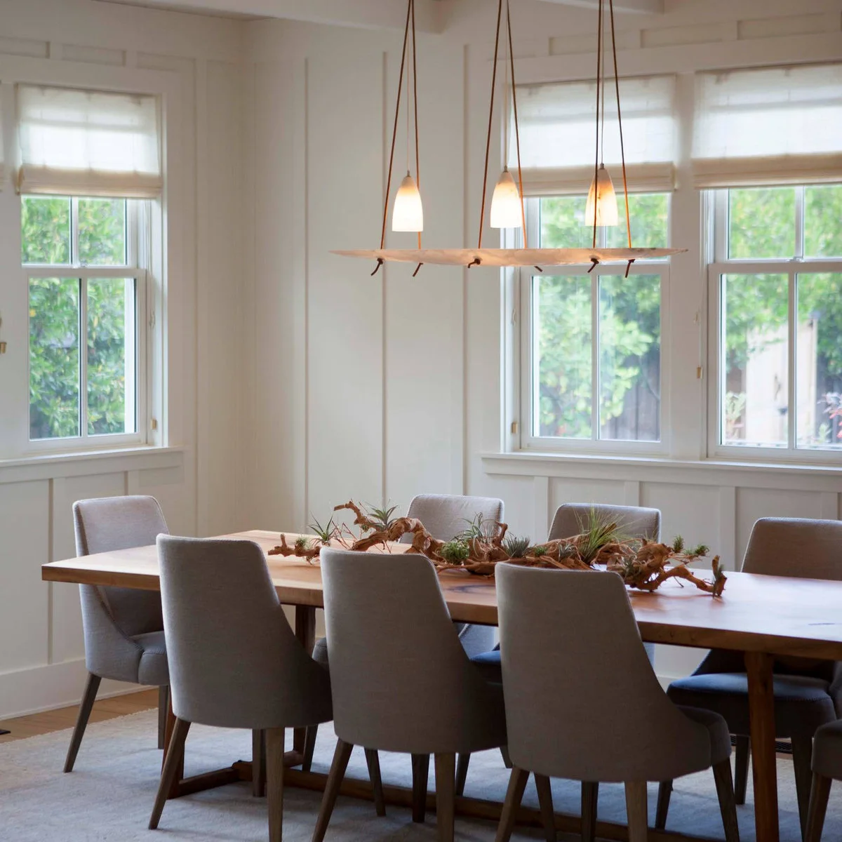Tall white vertical wall divisions around dining-room windows above gray chairs