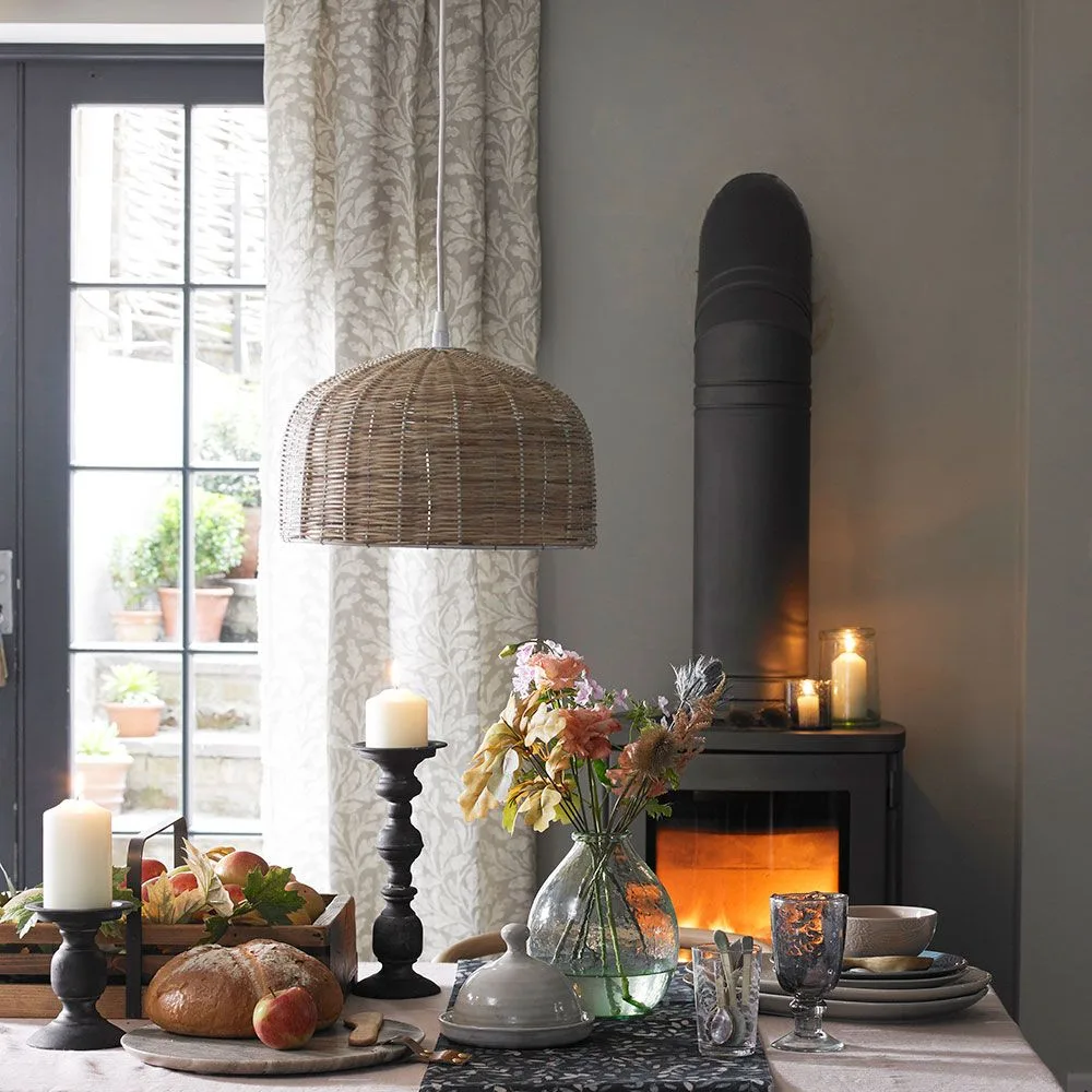 Pale leaf-pattern dining curtains beside a glazed door and a dark stove with a tall flue