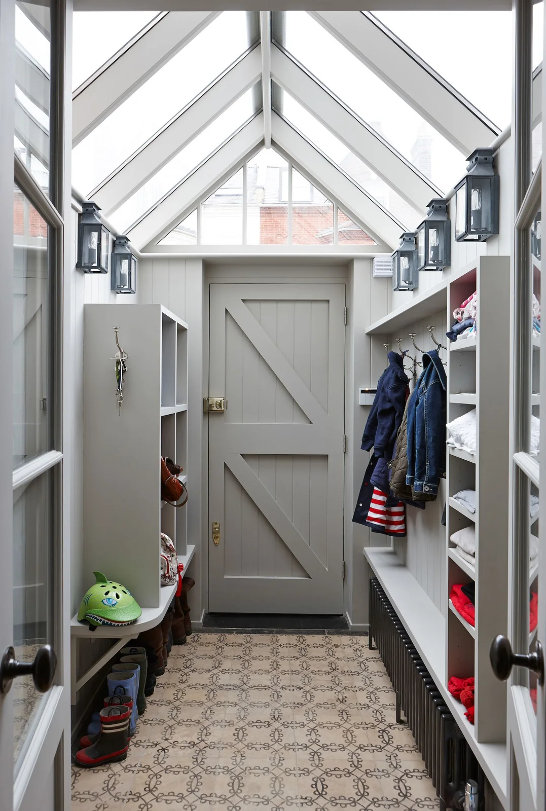 A pale glazed entrance porch contains a boarded exterior door, open coat and shoe compartments, dark lantern lights and a patterned floor