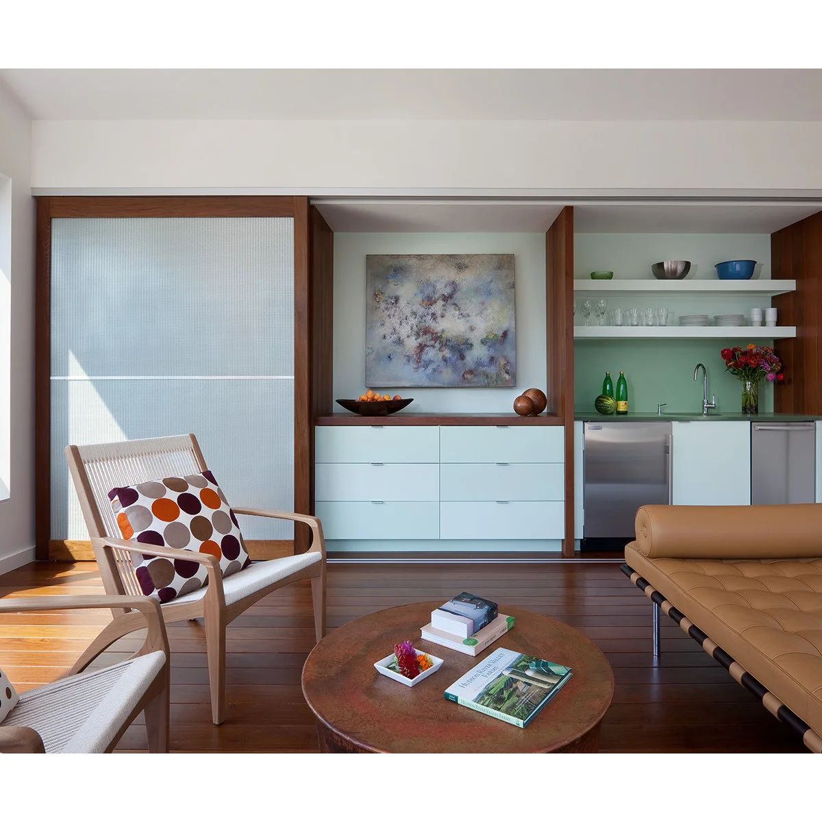 Mint-colored sliding panels beside a kitchenette sink, open shelves and a small refrigerator
