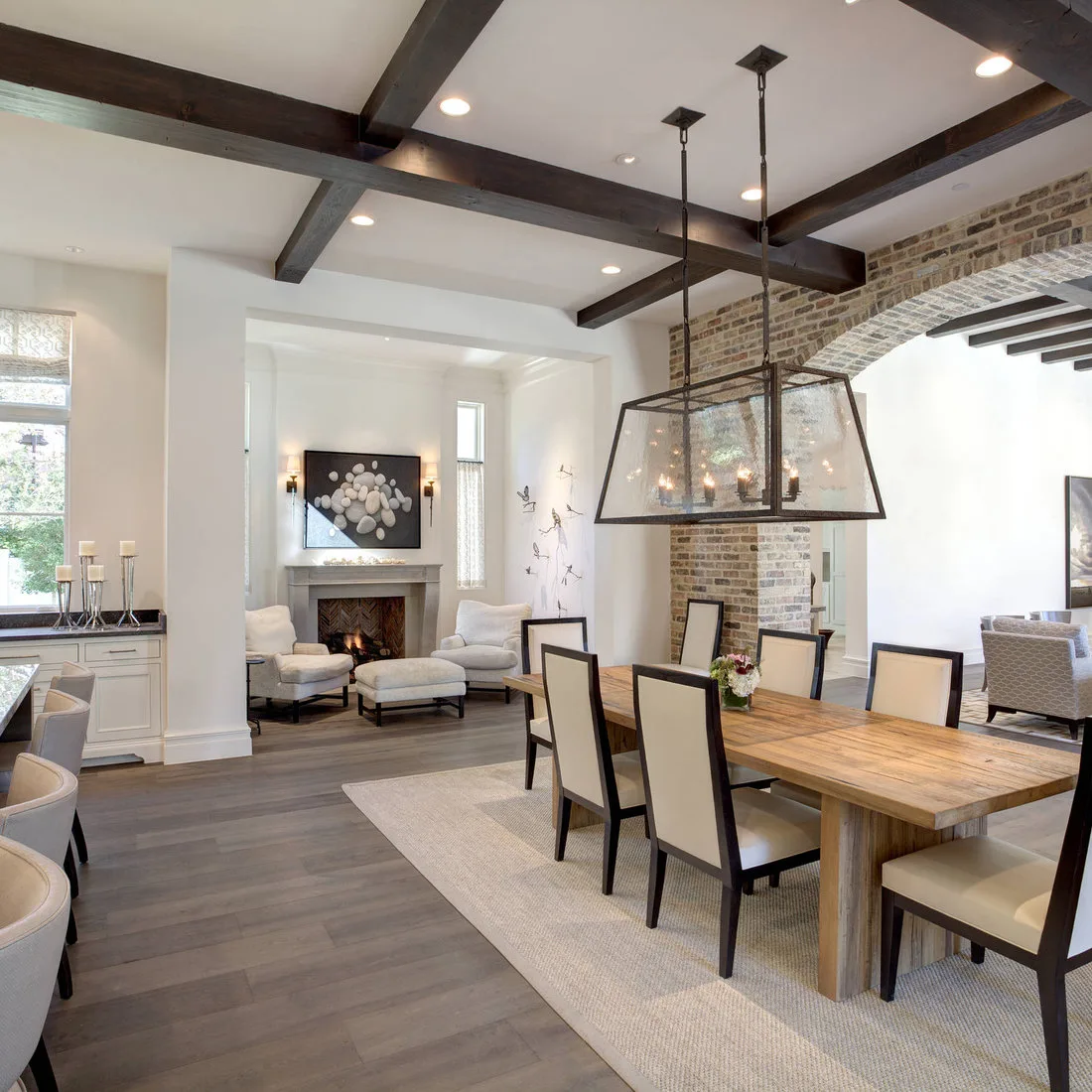 Pale rectangular rug under a wood dining table and cream chairs beside an open living area