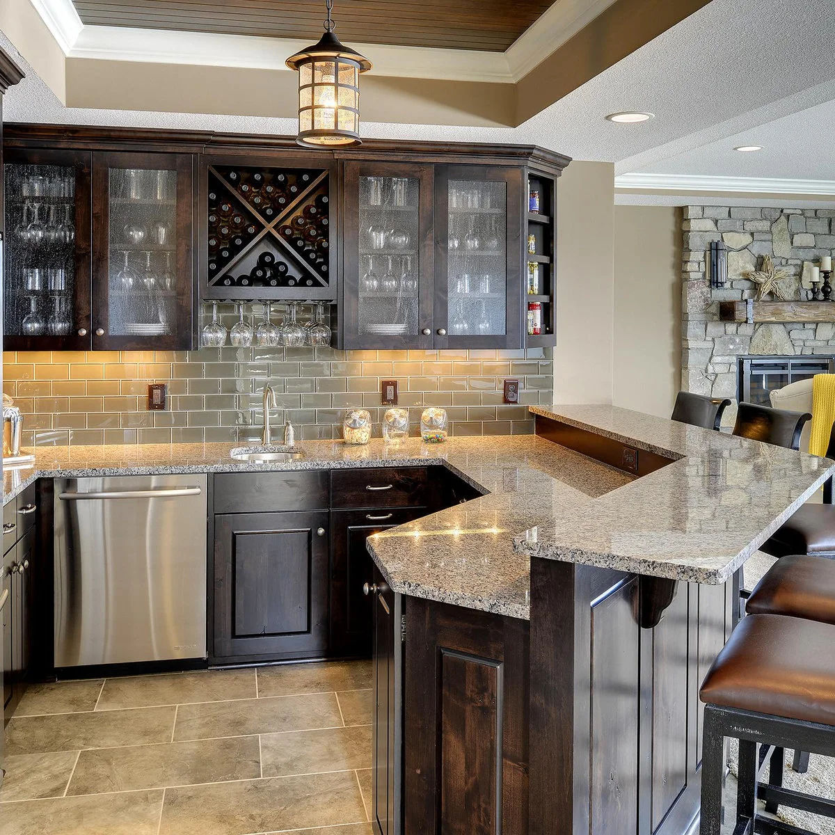 U-shaped basement wet bar with dark cabinets, pale counter and raised seating edge