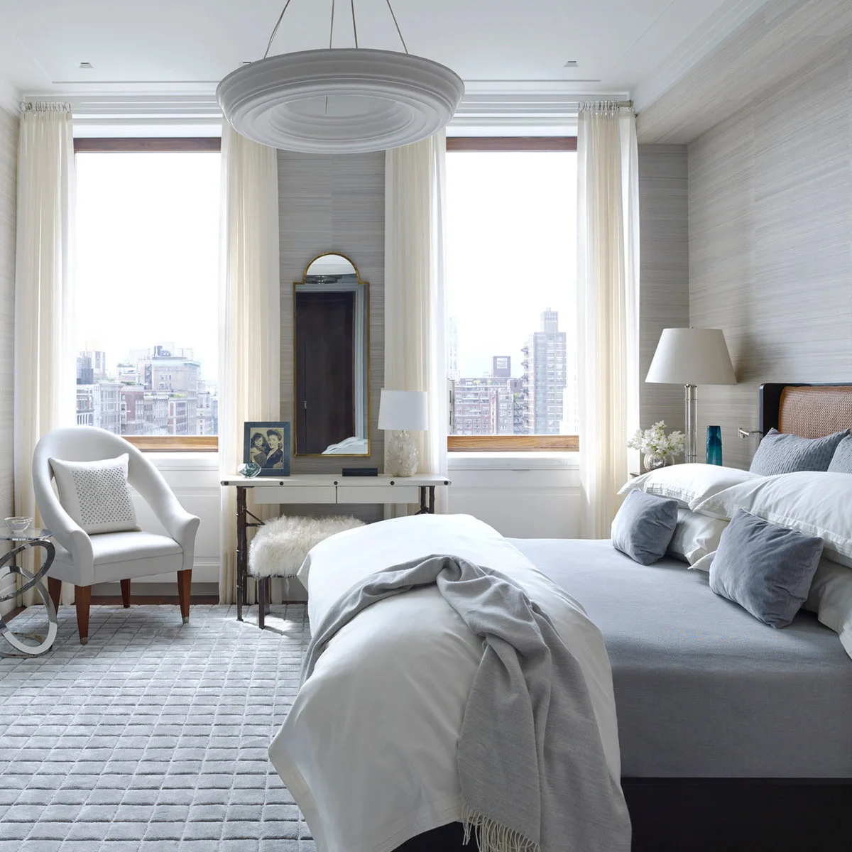 Textured grey bedroom walls with pale curtains, grey bedding and a narrow dressing table