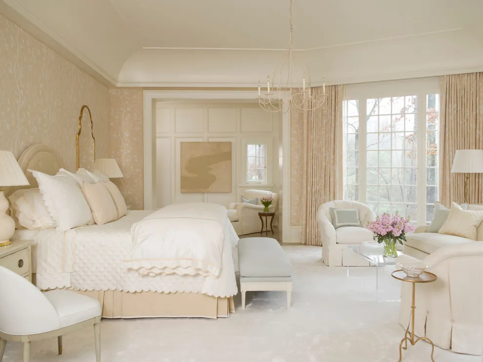 A pale beige bed sits beside light curtains and cream walls