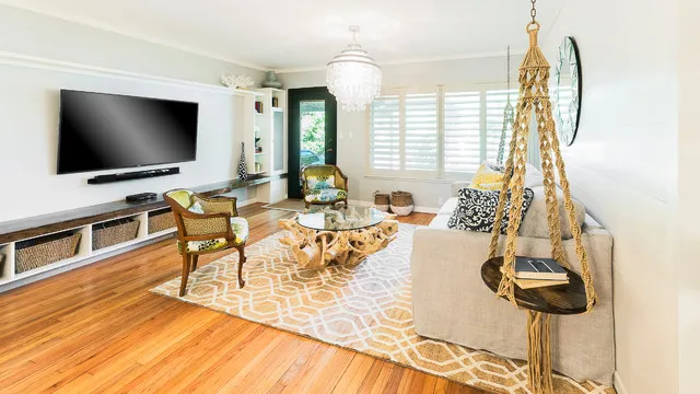 A pale seating area faces a long timber media unit beside woven furniture and a light rug.