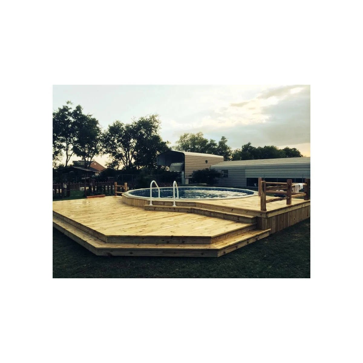 Round pool with exposed pale rim inside a low wood deck with broad steps and a small rail section at one side.