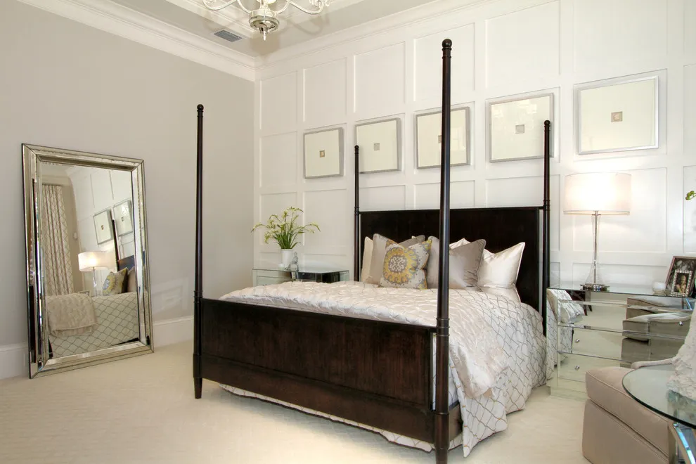 Pale wall panels sit behind a dark four-poster bed and a row of pictures