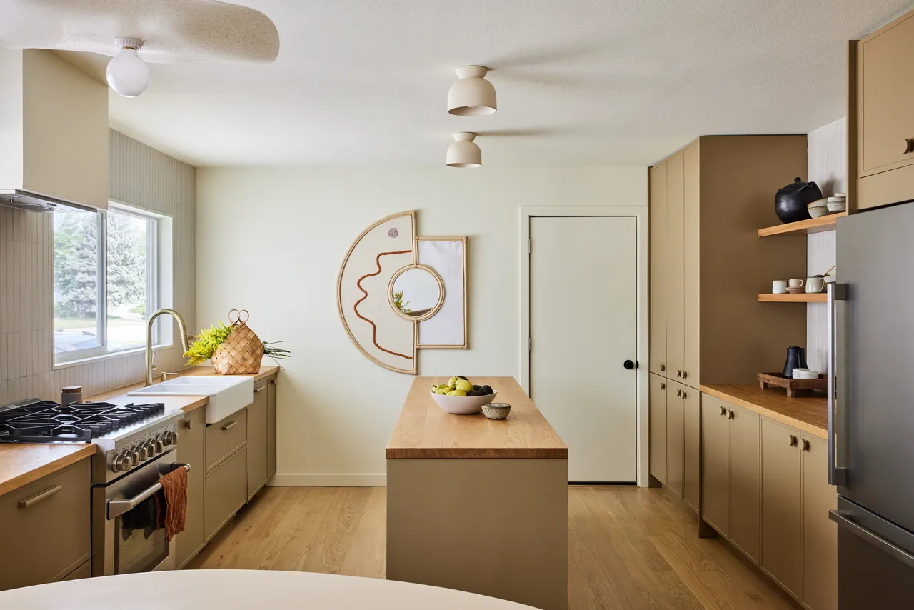 Pale beige doors surround a kitchen with a small wood-fronted island and open shelves