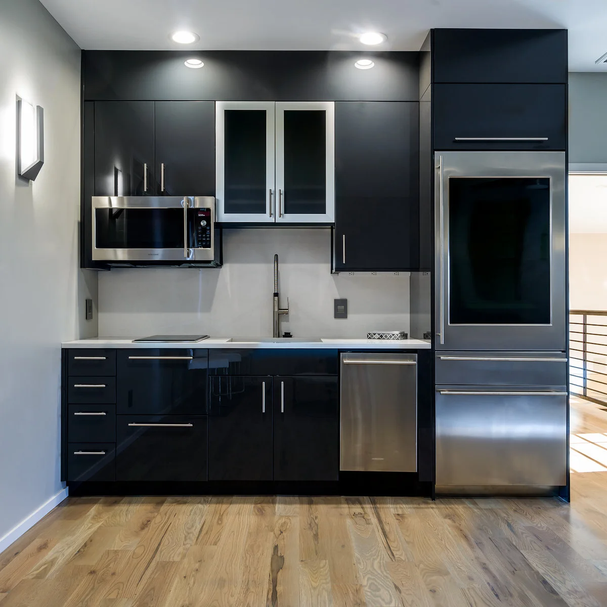 Dark compact kitchenette with a microwave, small cooktop, sink, dishwasher and tall refrigerator
