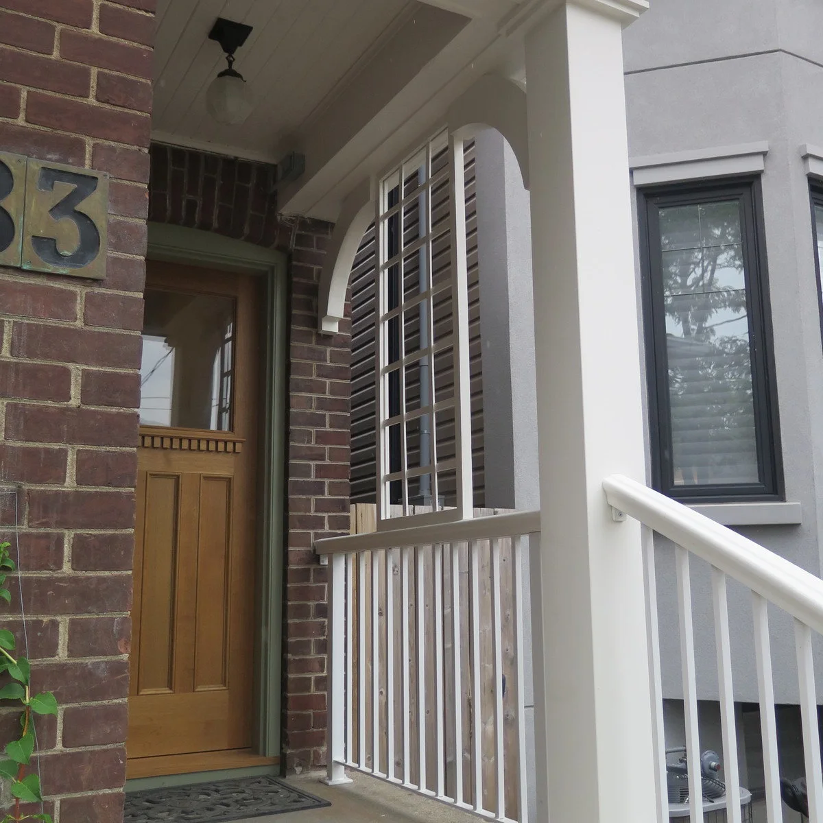 Small brick entrance with a pale side lattice, white railings and a wood-colored door