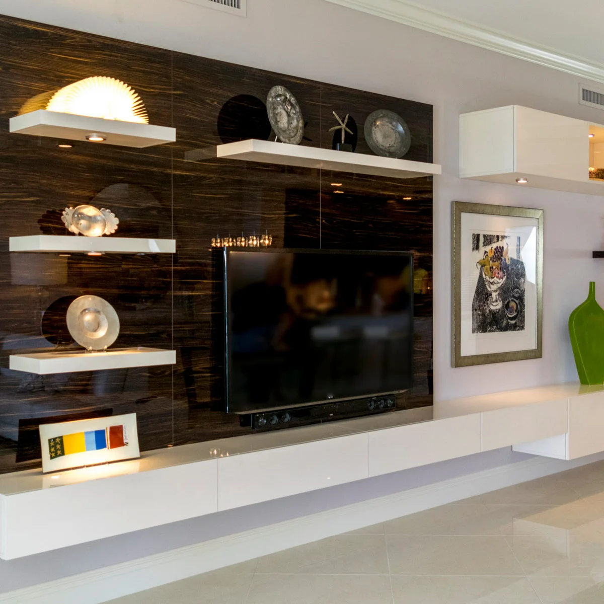 Pale shelf with decorative plates and a star-shaped object above a television on a dark glossy wall.
