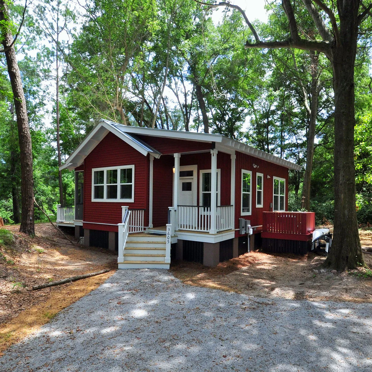 Small red house with a white-railed covered front porch and central steps facing the entrance