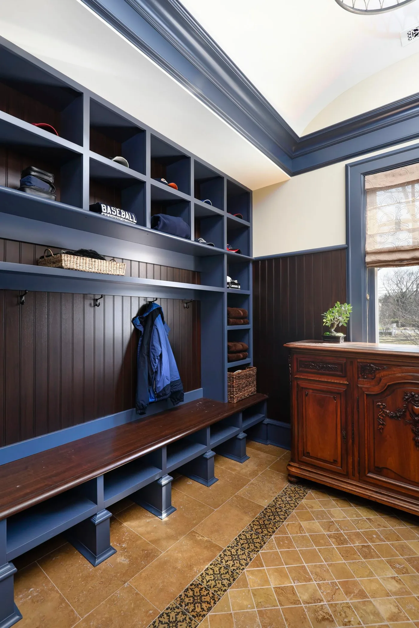 Blue mudroom shelves and bench beside a carved wooden chest on a warm patterned floor.