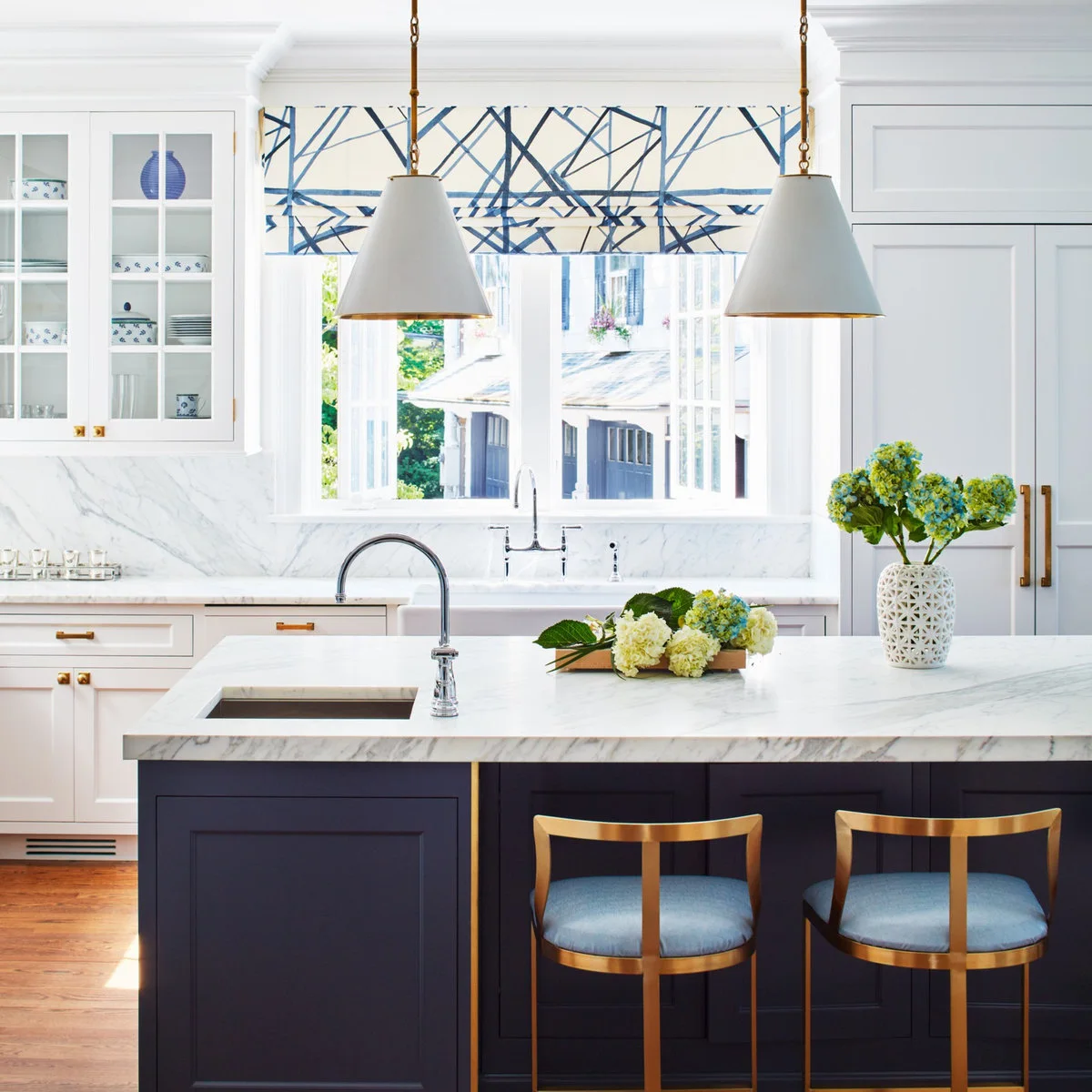 Low-backed gold-colored stools with blue seats beside a navy kitchen island