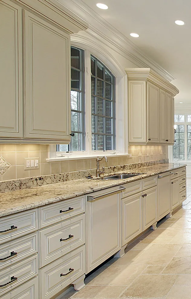 Soft white cabinets with layered moldings extend around an arched window