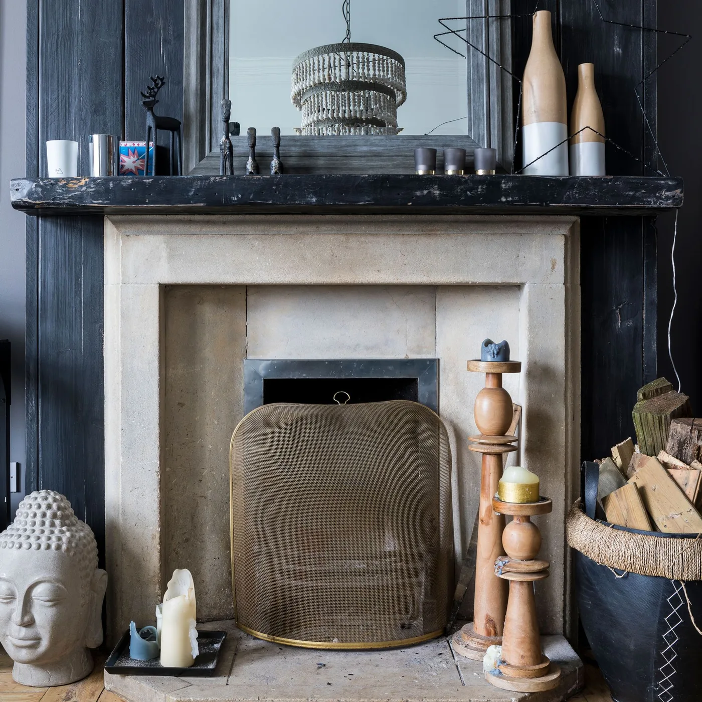 Pale fireplace beneath dark paneling with a curved metal screen and small unlit candles at different hearth positions.
