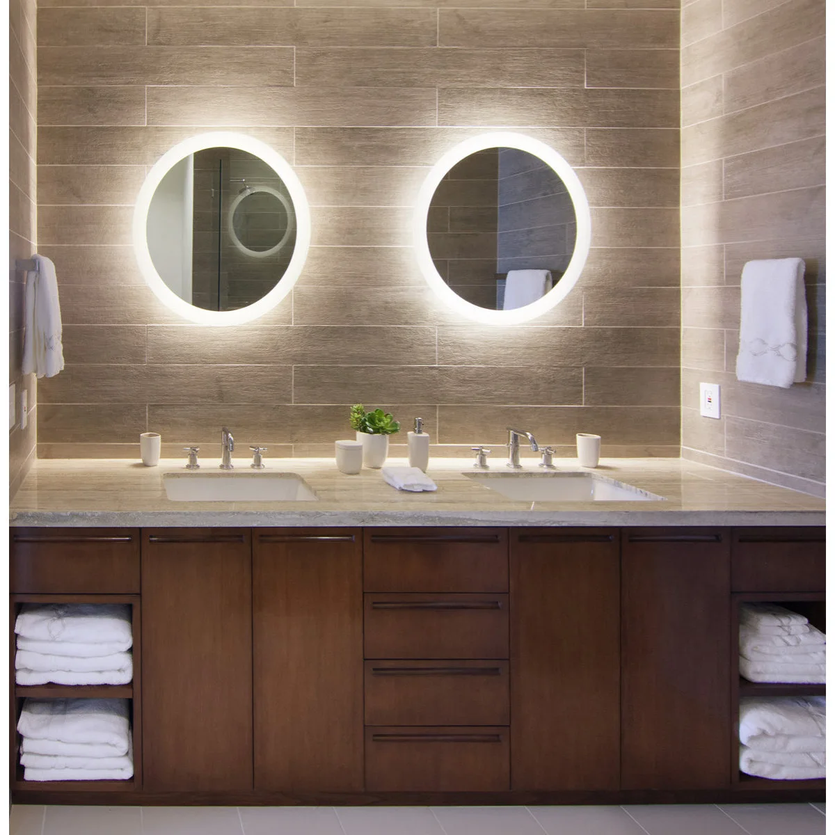 Wood double vanity with horizontal wall tiles, illuminated round mirrors and small white counter accessories.
