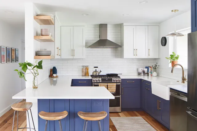 Blue lower cabinets and a small island sit beneath white uppers and a simple hood.
